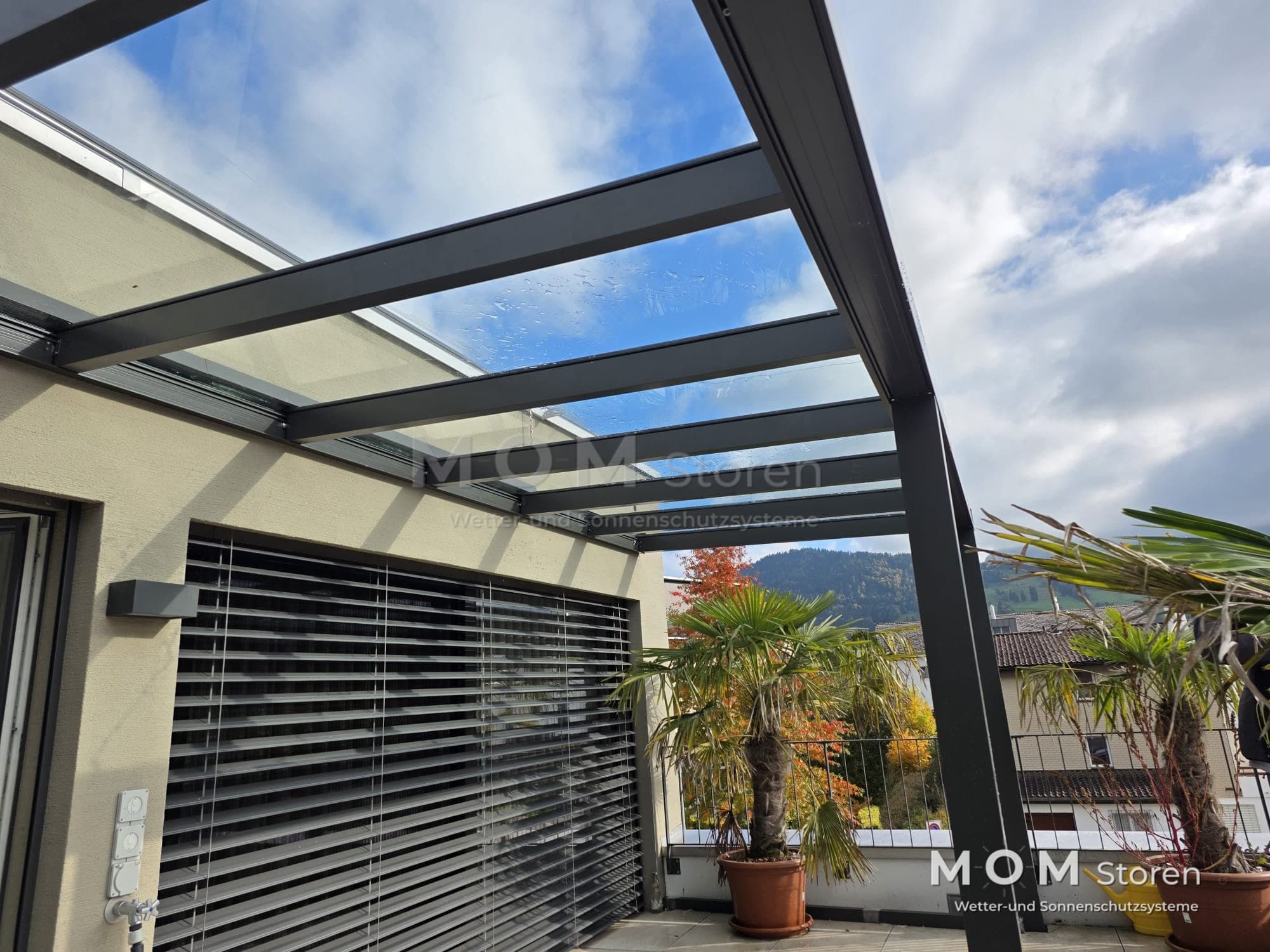 Dark-framed glass roof above a terrace