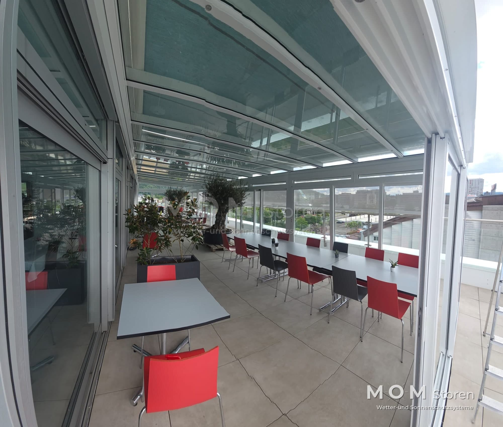 Glass façade and roof around a furnished outdoor area