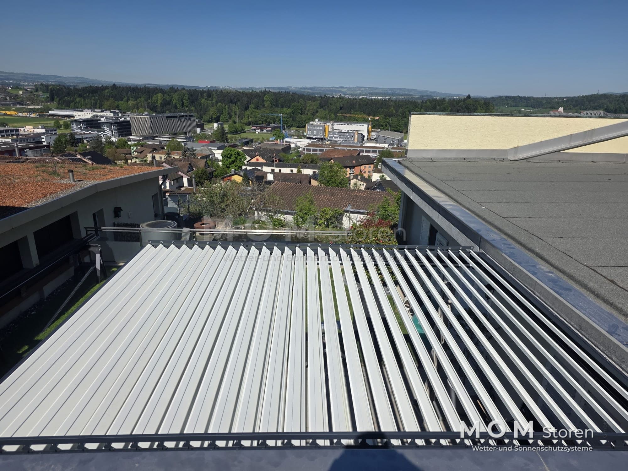 White louvred roof from above with rooftops beyond